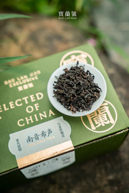 Oolong tea leaves in a white bowl on a green tea gift box