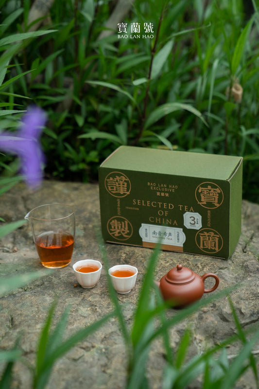 Green tea box with brand logos beside small tea cups and a brown teapot