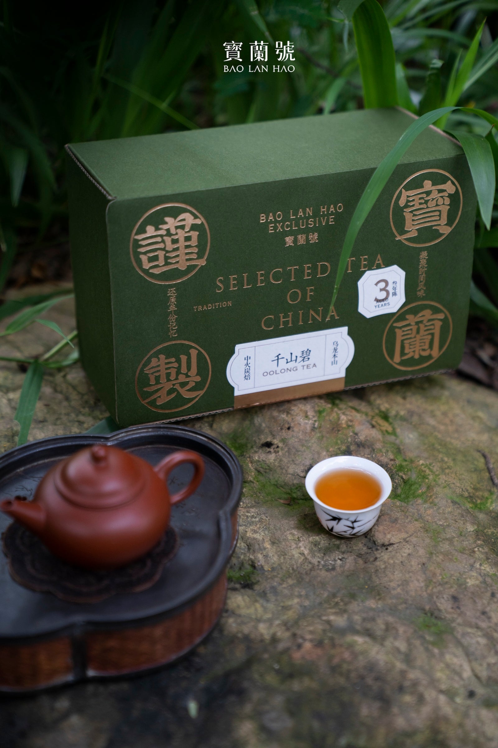 Dark green Bao Lan Hao oolong tea box with orange tea cup and brown teapot on tray