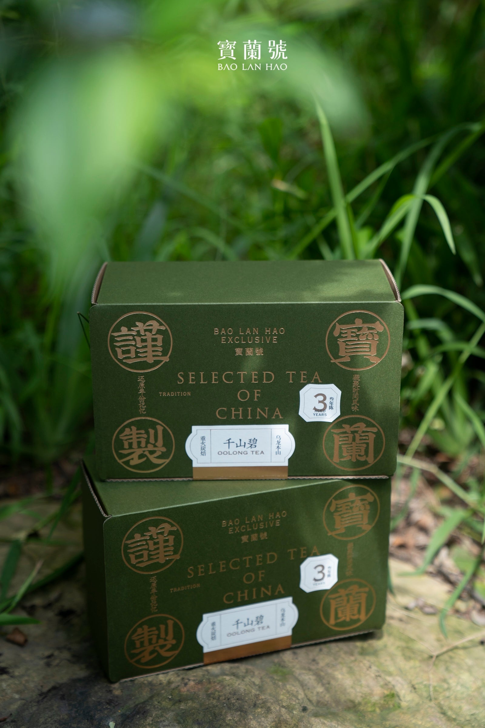Stacked green tea boxes on a rock with grass in the background