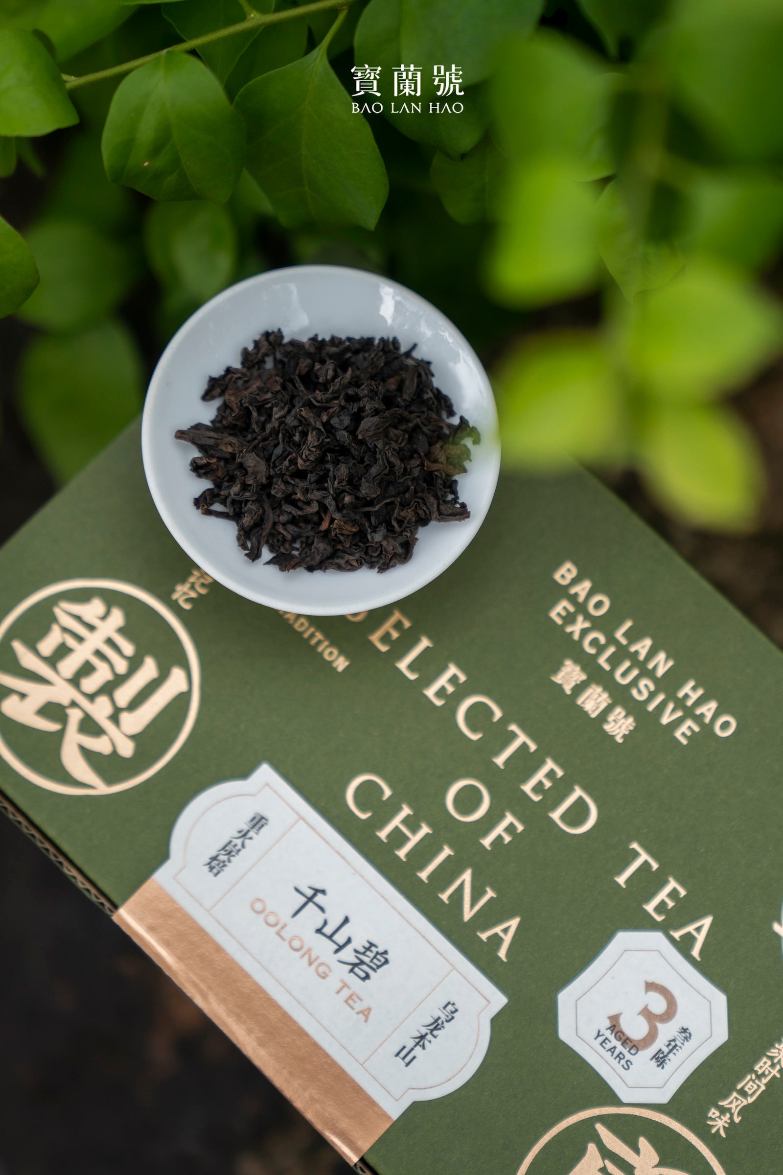 Small bowl of dark loose tea beside a green “Selected Tea of China” box